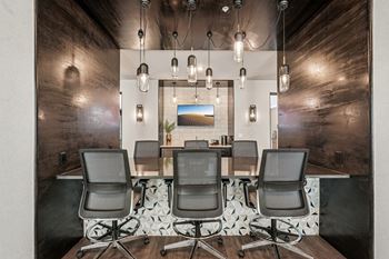 A modern office with a wooden floor and a long table with four chairs